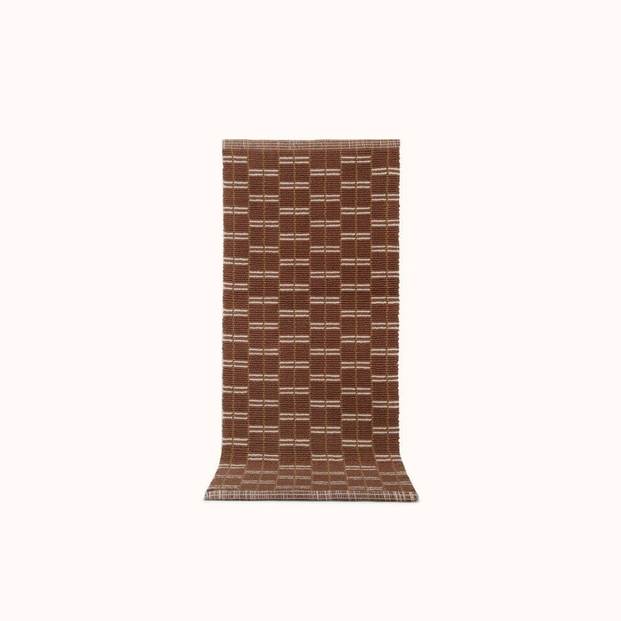 A brown and natural colored runner mat with a geometric pattern, displayed on a plain background.