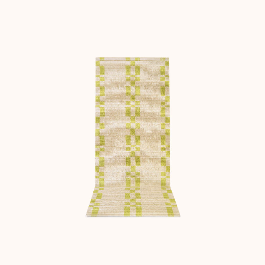 A rectangular, bath mat with a geometric pattern in lime and ecru colors.