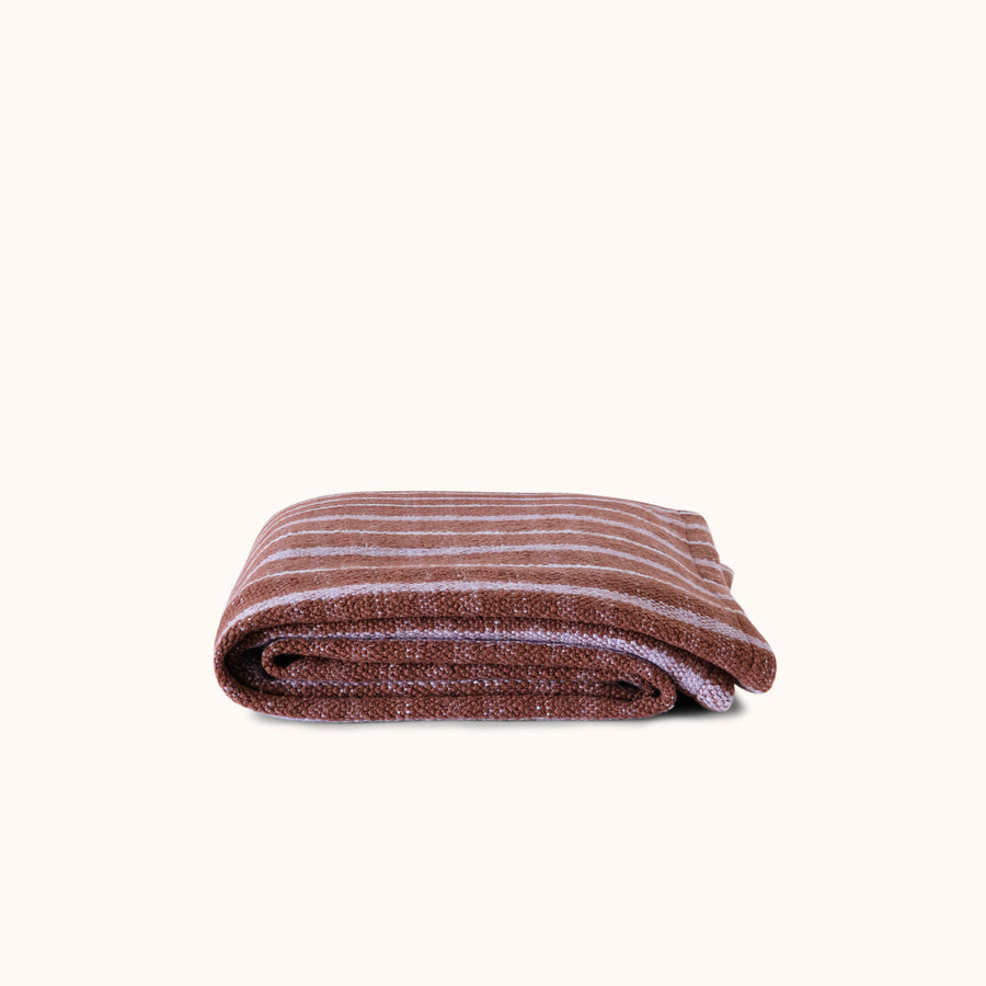 Folded brown and lavender woven check blanket on a white background