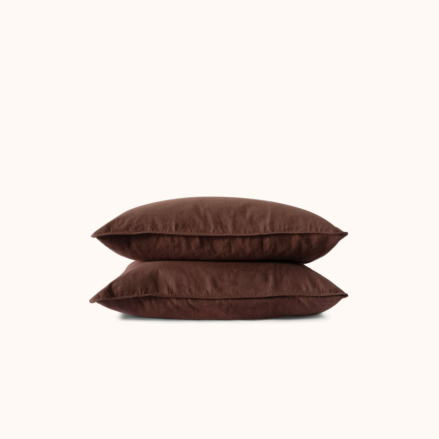 Two brown pillows stacked neatly against a white background 