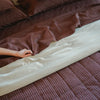Morrow Soft Goods Pairing of Juno Check Quilt with Hemp Cotton Sheets in Brun and Duvet Cover in Oat - close lifestyle image