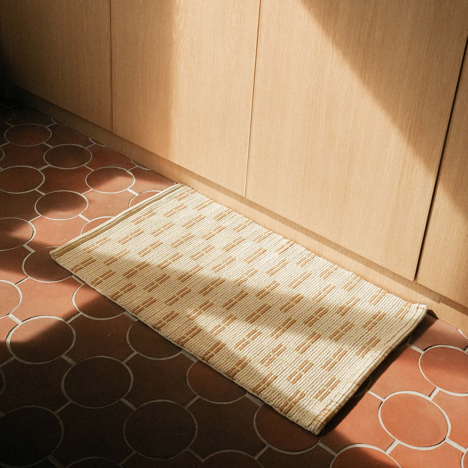 A natural colored mat featuring a geometric design in brown and lime.