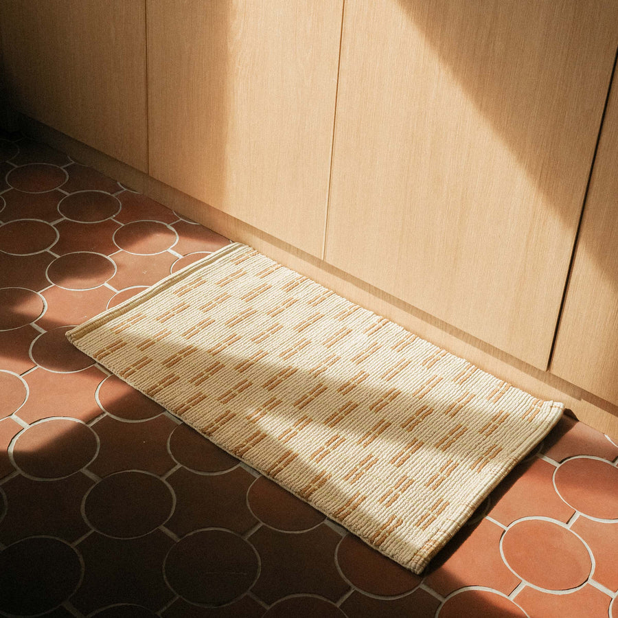 A natural colored mat featuring a geometric design in brown and lime.