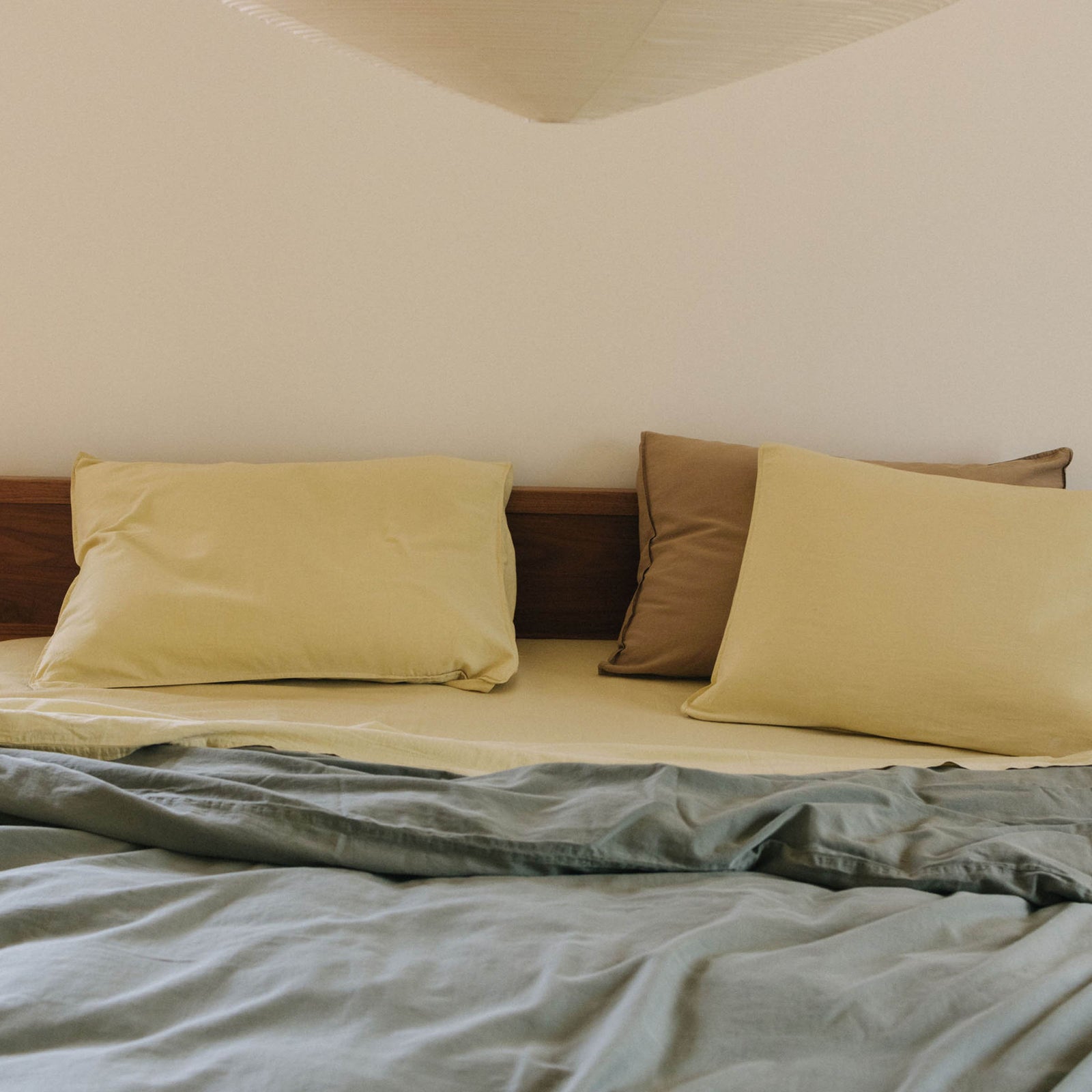 A bed with yellow and brown pillows and a yellow and green bed coverings 