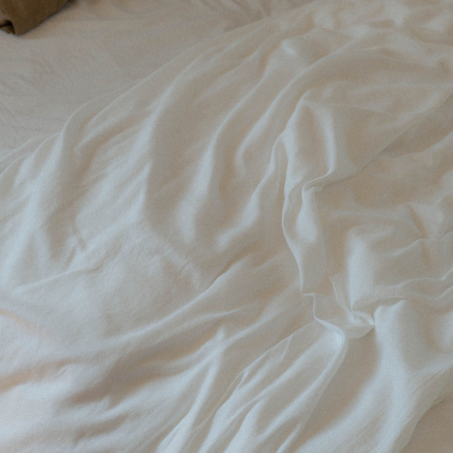 A close up of a slightly wrinkled organic white matte sateen sheet 
