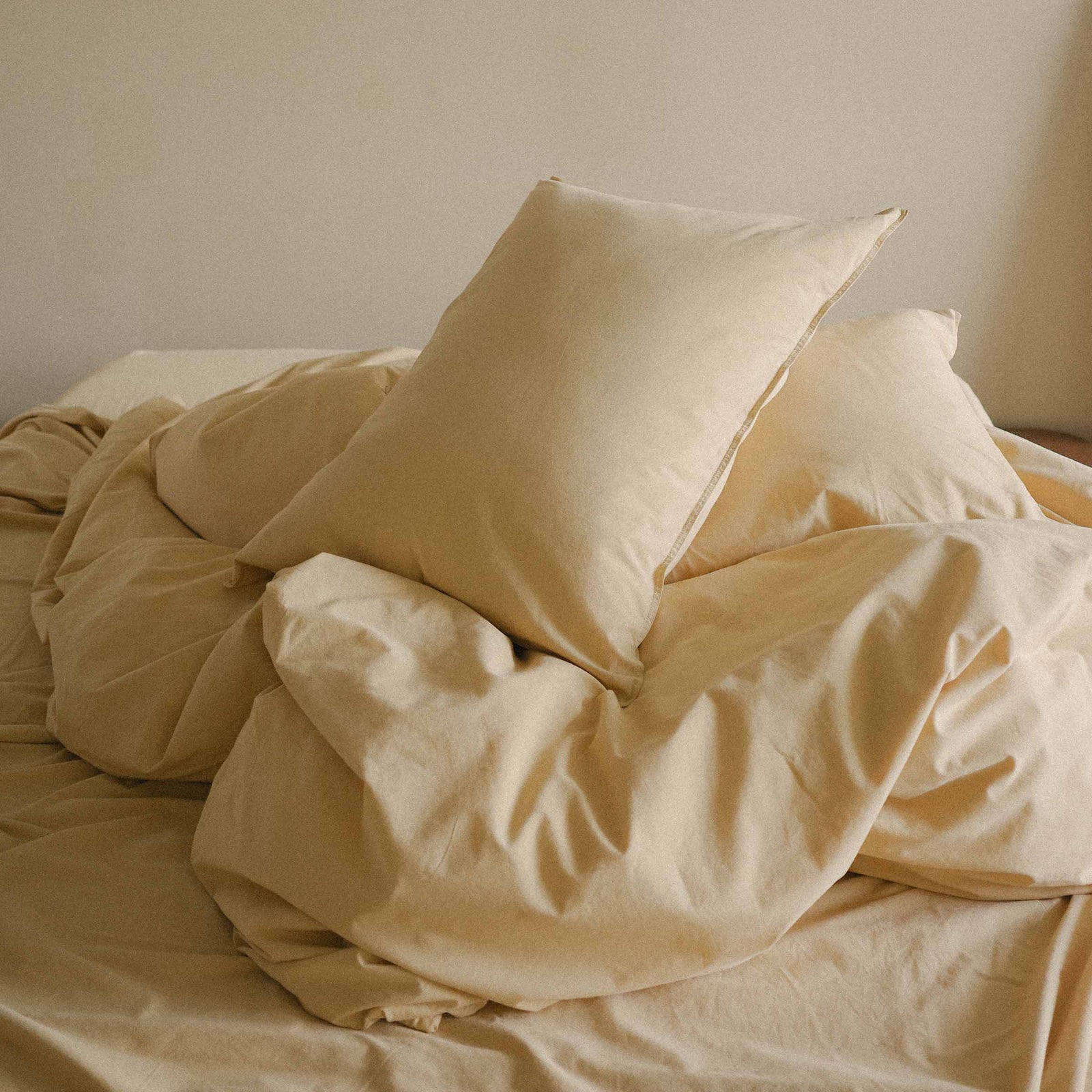 Yellow bedding with pillows on a bed in a softly lit room