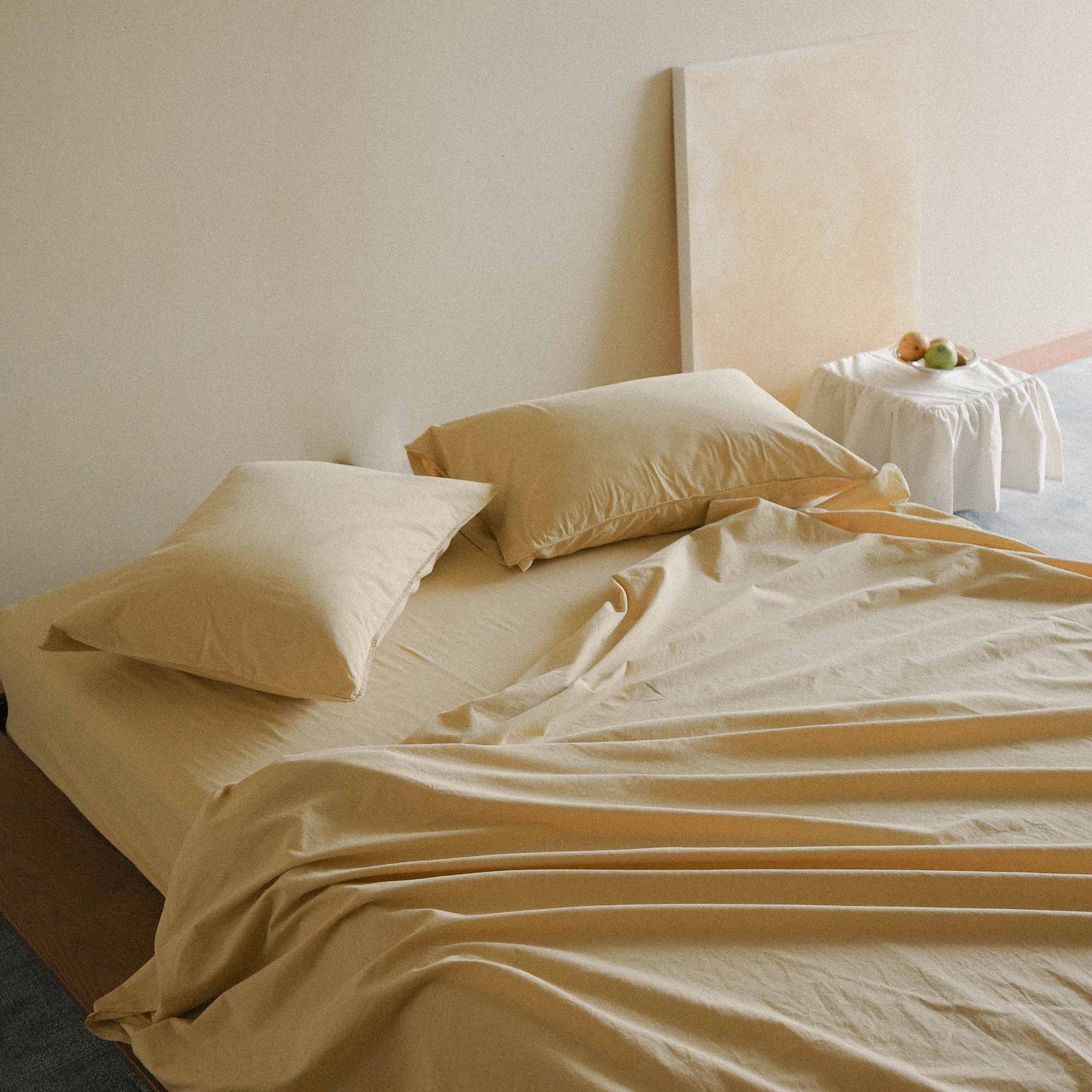 Yellow bed with pillows and sheets in a minimalistic room.