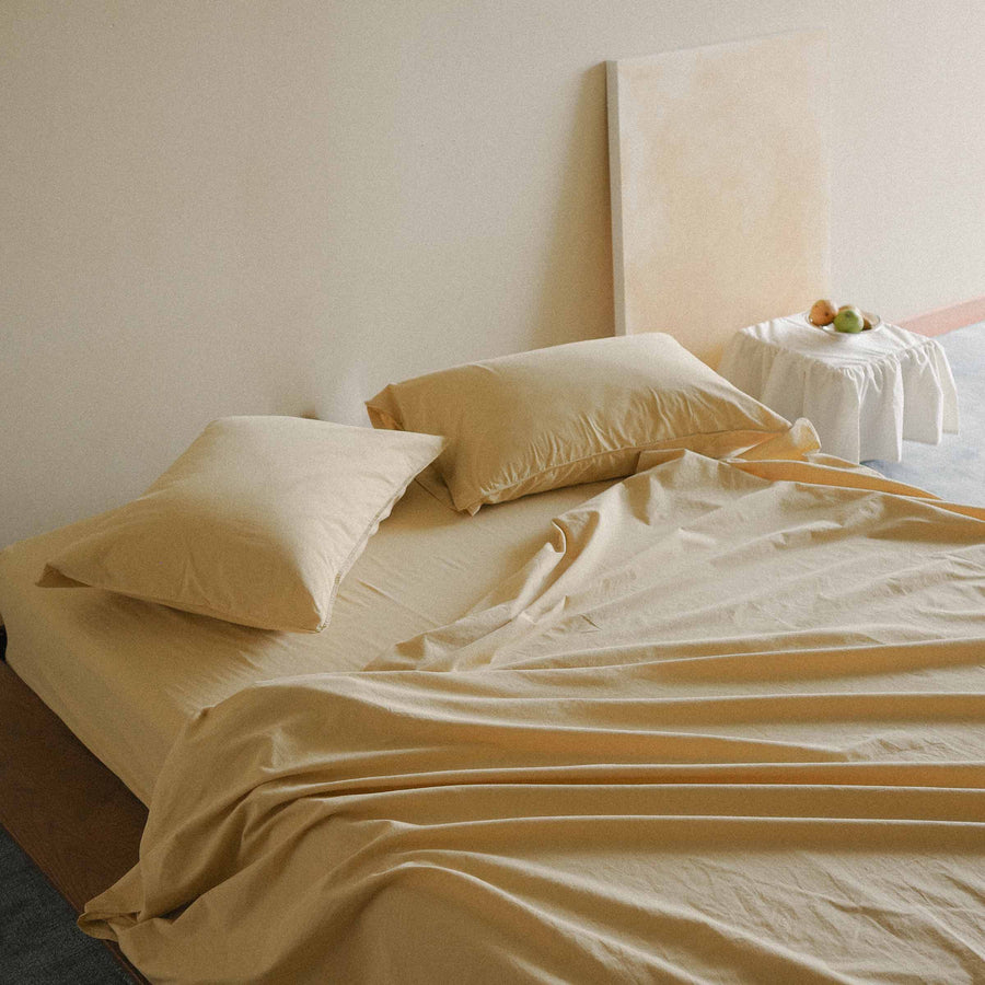 Yellow bed with pillows and sheets in a minimalistic room.