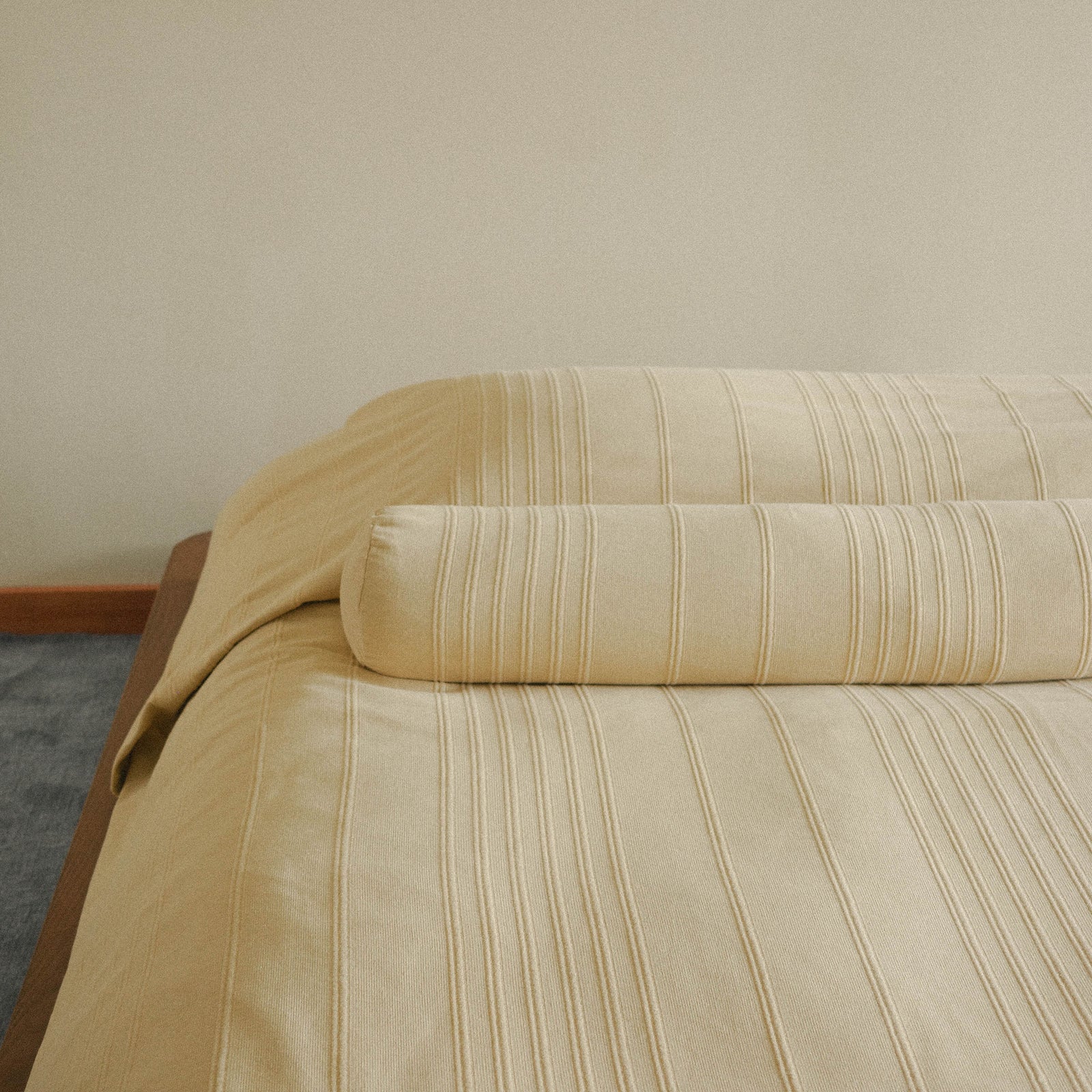 Morrow Soft Goods Devi Coverlet and Devi Bolster in Maiz - Cropped image of made bed