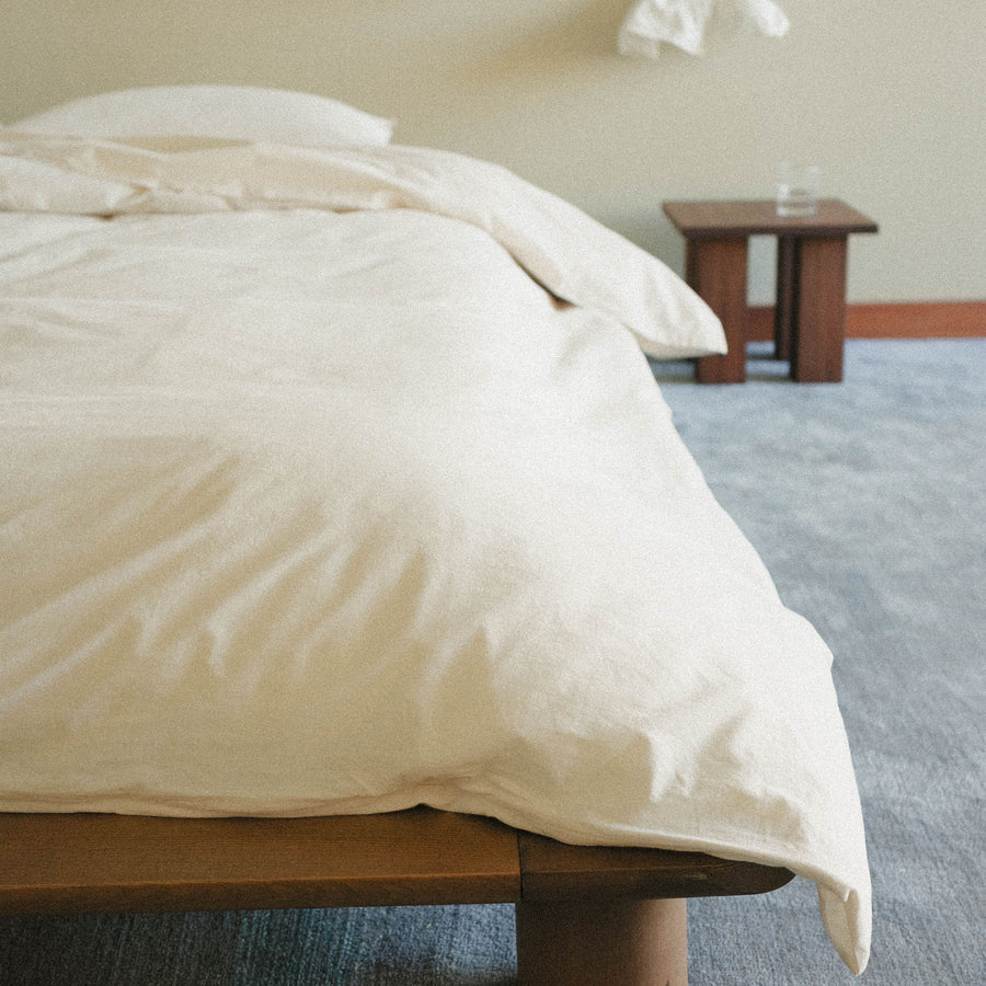 Cream duvet cover on a bed with a blurred room background