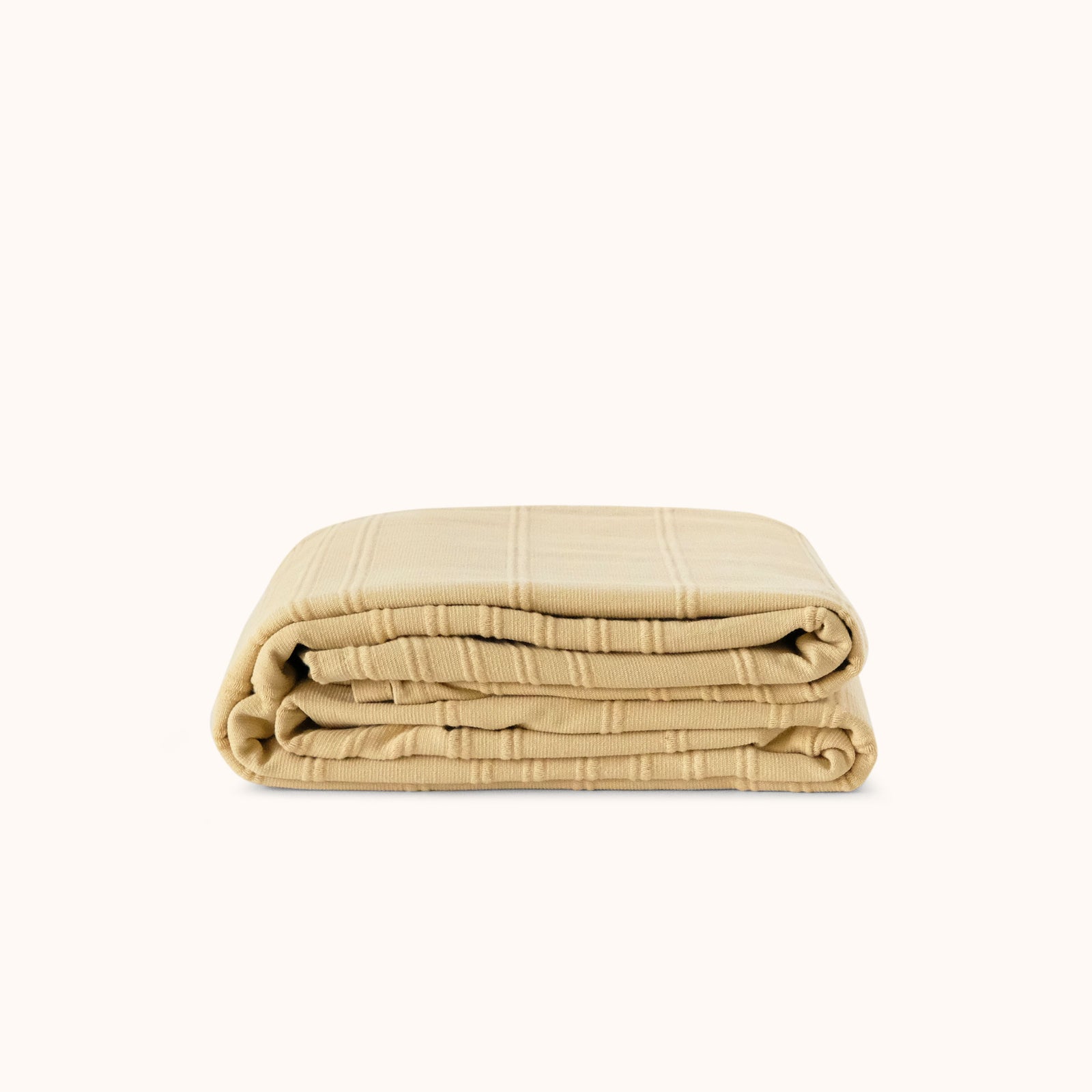 Folded beige / yellow blanket against a white background