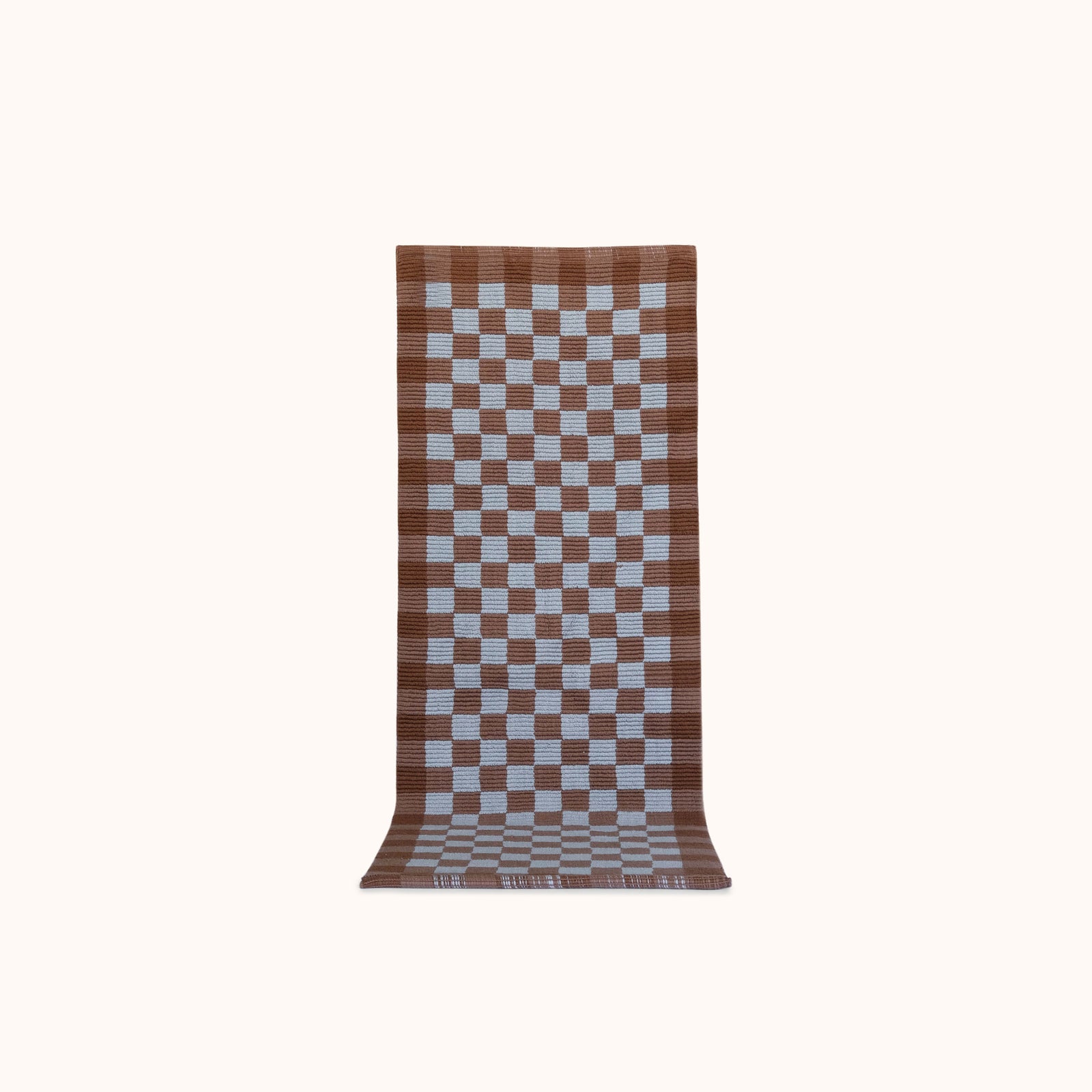 A long rectangular woven mat with a brown and light blue checkerboard pattern, displayed flat against a solid off-white background.