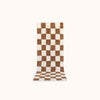A long rectangular plush bath mat with a brown and off-white checkerboard pattern, shown flat against a solid off-white background.