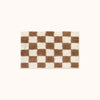 A rectangular plush bath mat with a brown and cream checkerboard pattern, centered on a solid off-white background.