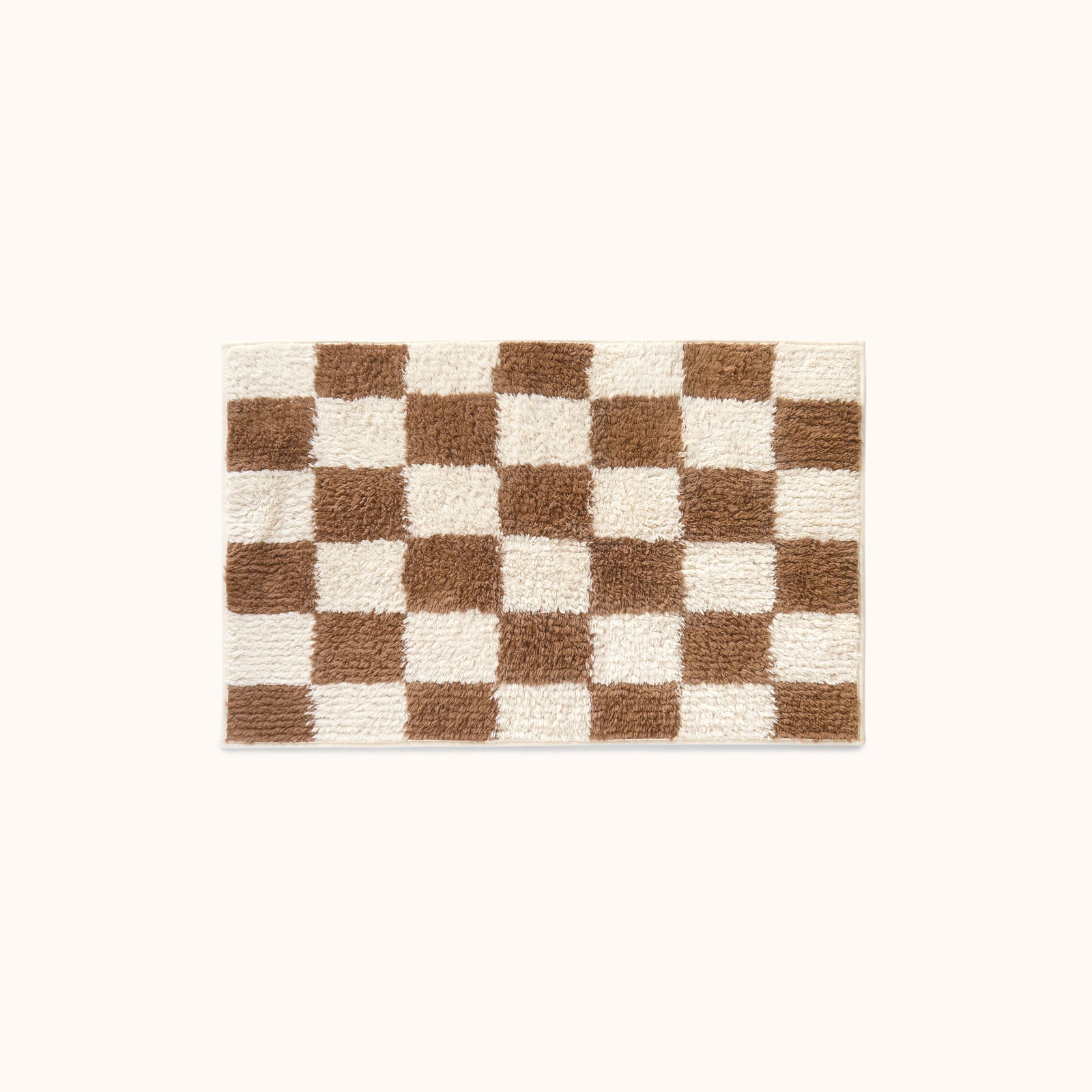 A rectangular plush bath mat with a brown and cream checkerboard pattern, centered on a solid off-white background.