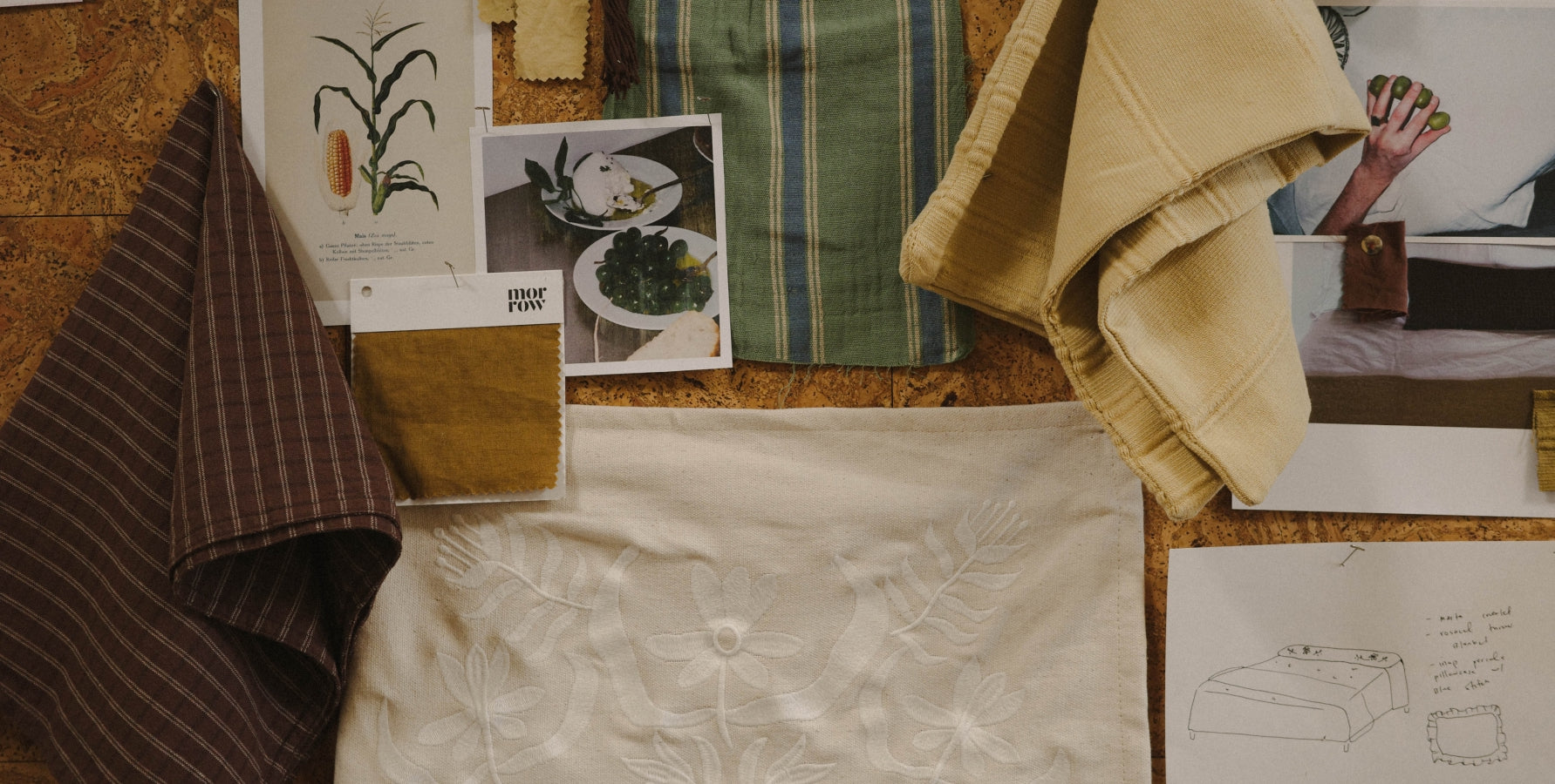 A styled flat-lay of fabric and textile swatches pinned to a cork board.