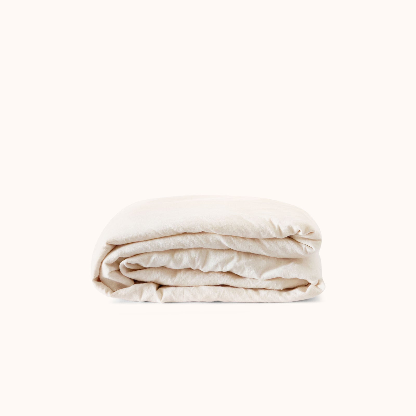 Folded cream fitted sheet on a white background