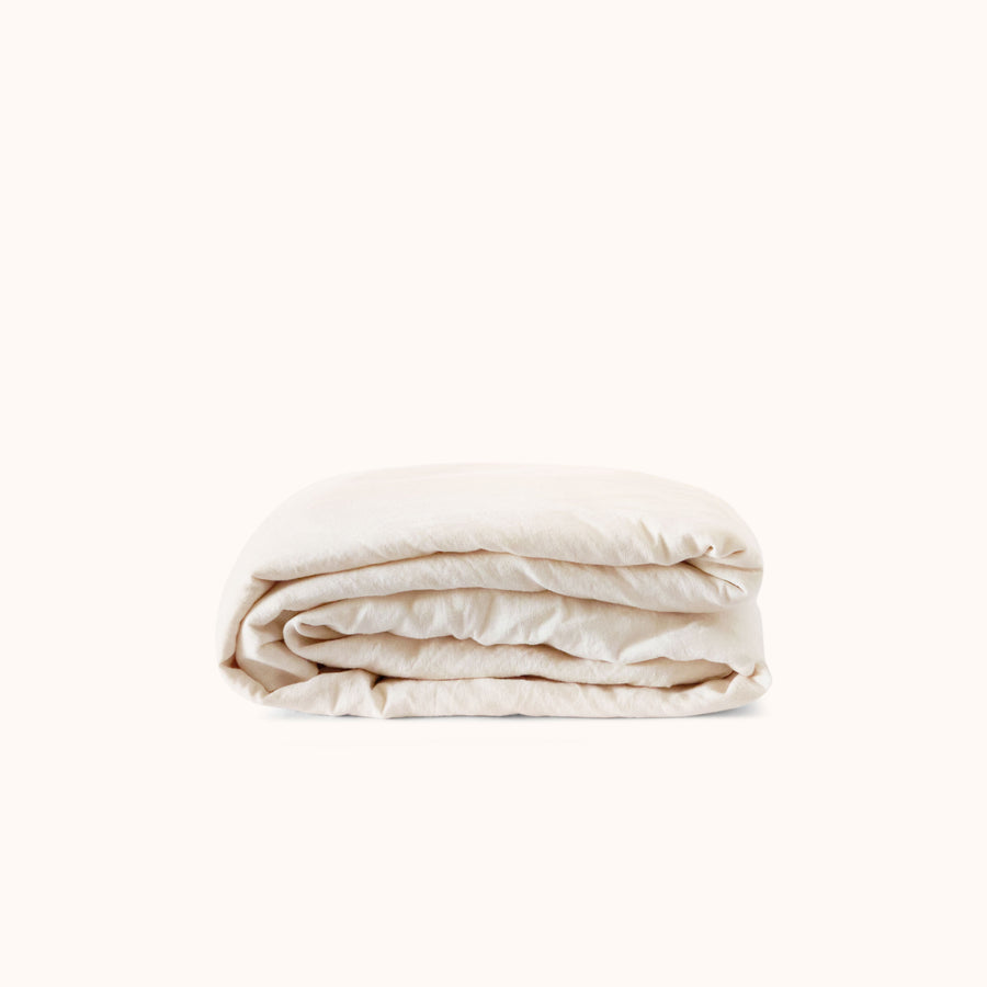 Folded cream fitted sheet on a white background