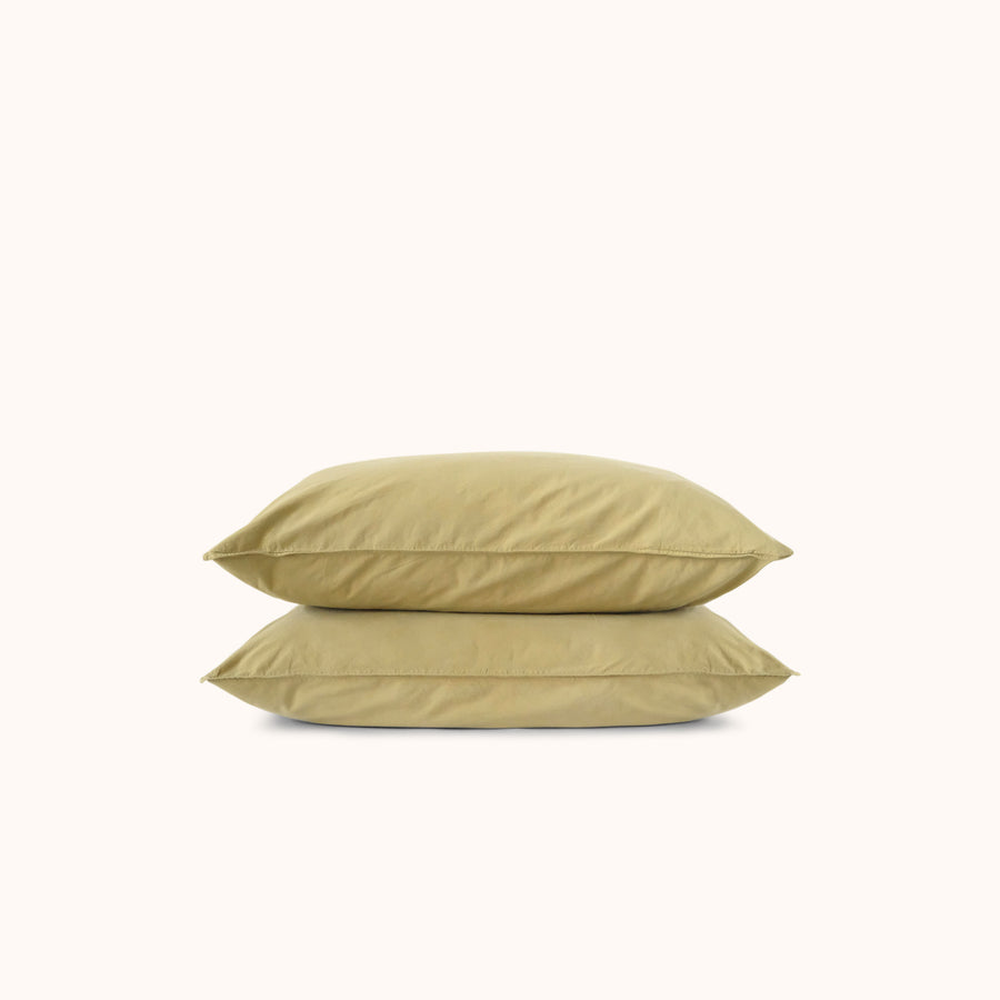 Two green pillows stacked on a white background