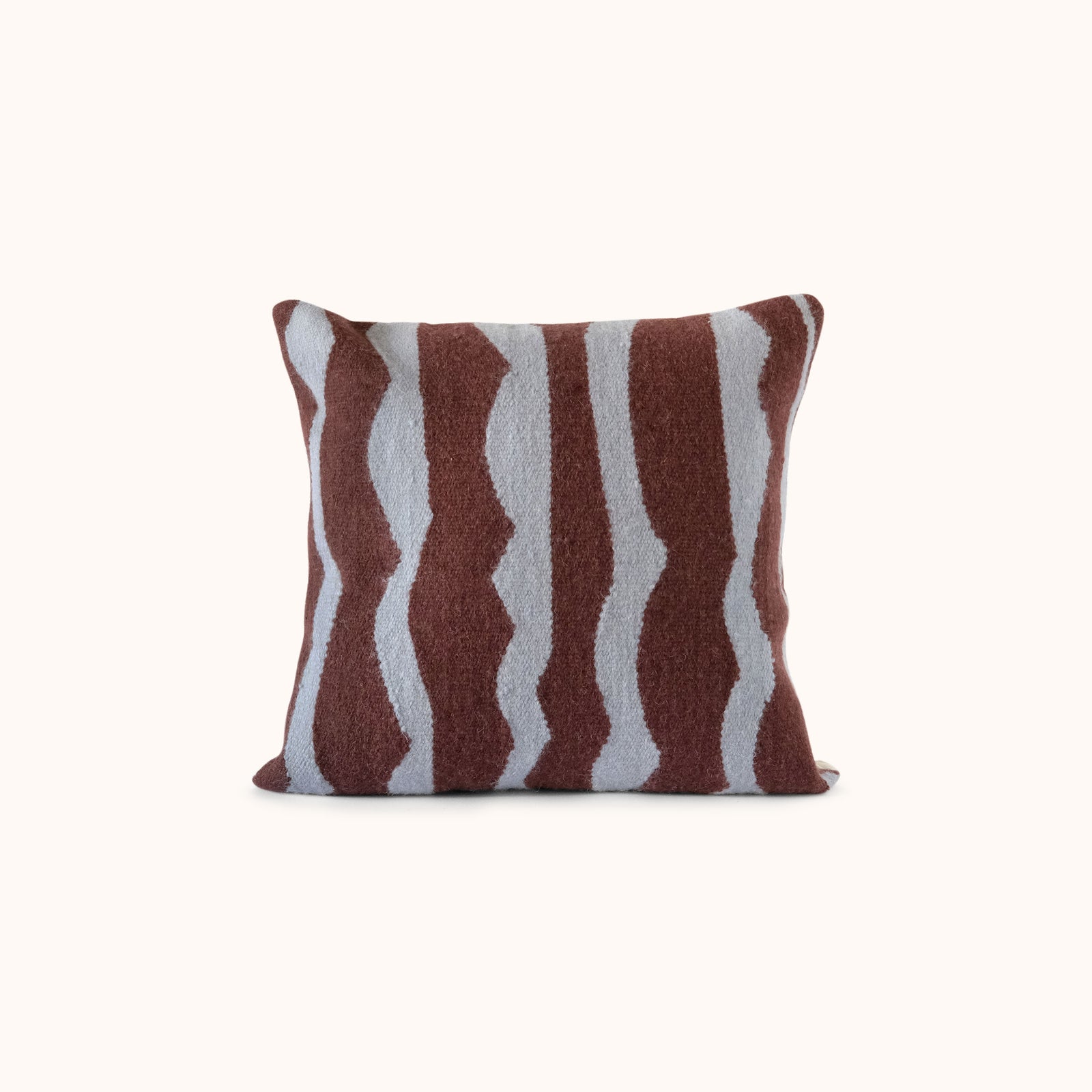 A square throw pillow featuring a textured, hand-knotted pattern of vertical wavy stripes in dark brown and light blue, set against a plain off-white background.