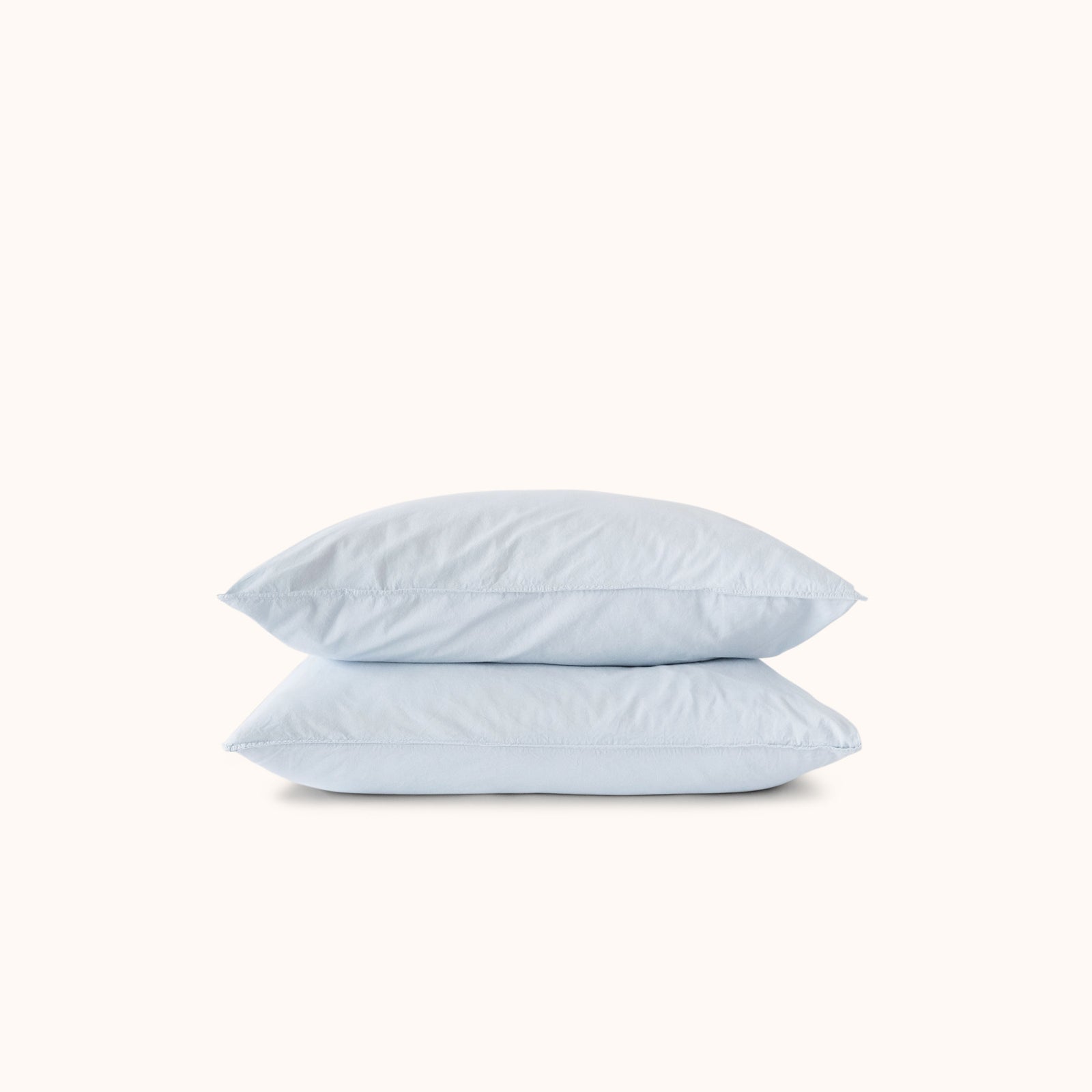 Two light blue pillows stacked on a white background