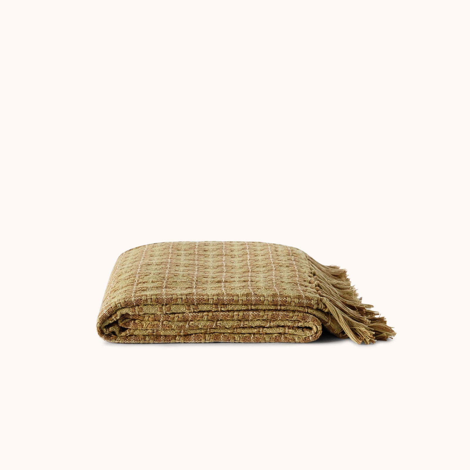 A folded patterned woven throw blanket in a textured tan and olive-brown pattern with fringed edges, displayed on a clean off-white background.