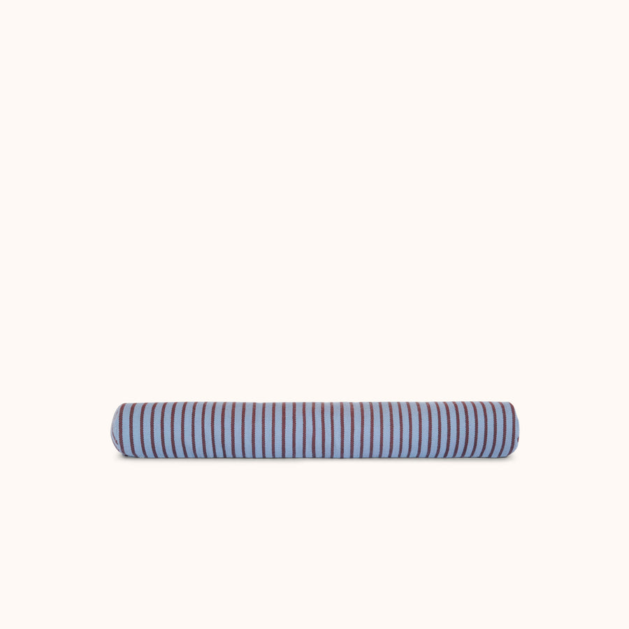 A long cylindrical bolster pillow with alternating blue and brown stripes