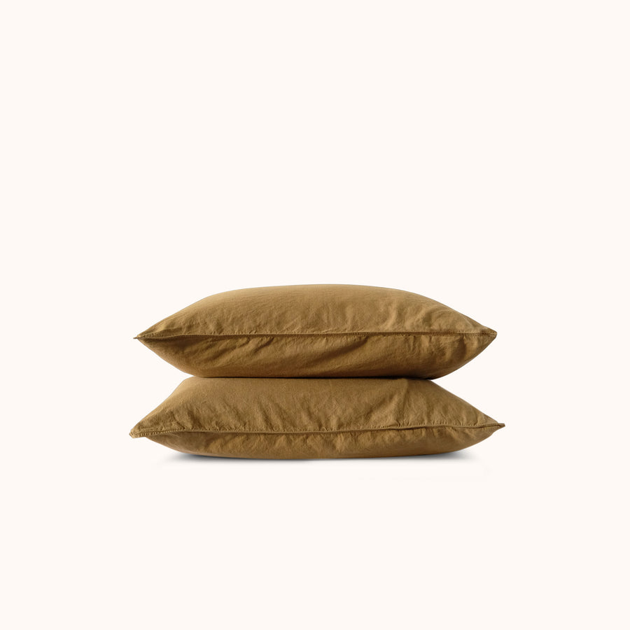Two brown pillows stacked neatly against a white background