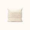 A cream color throw pillow with a textured pattern in the center.