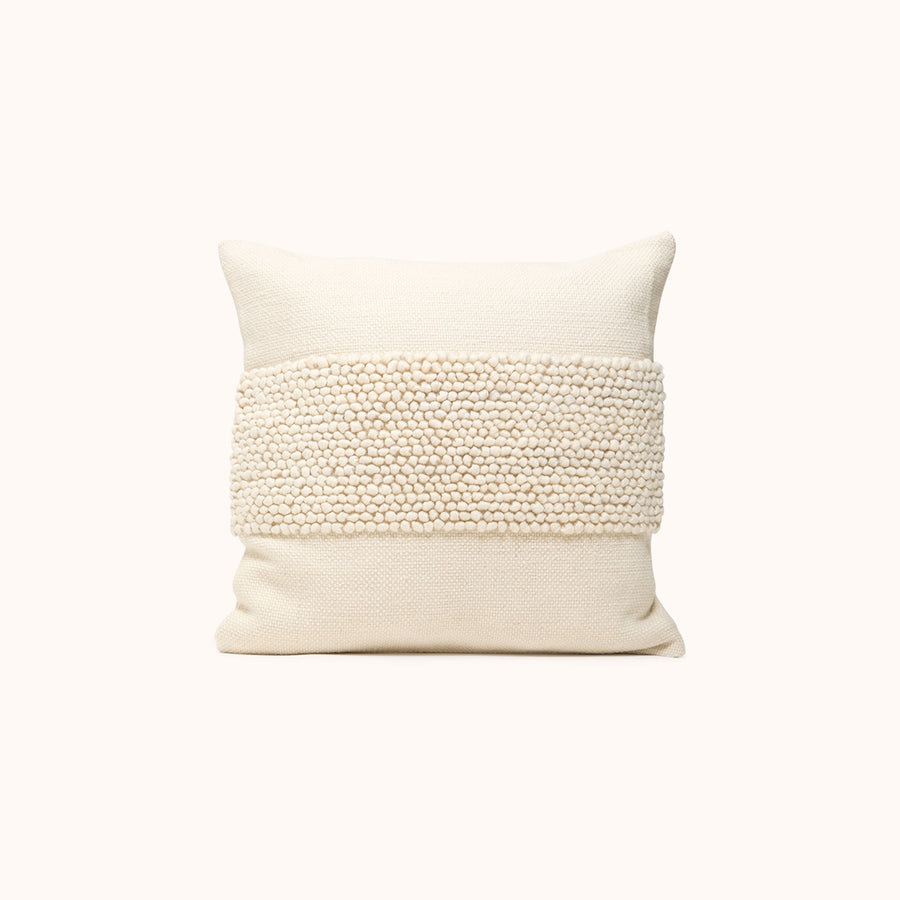 A cream color throw pillow with a textured pattern in the center.