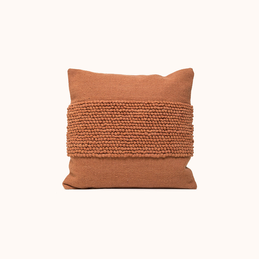 rust pillow with a textured band in the center on white background