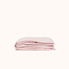 A folded pink fitted sheet against a white background