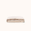 Folded Oat / cream fitted sheet made of matte sateen cotton on a white background