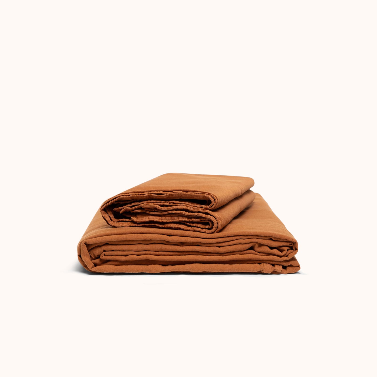 A folded terracotta organic matte sateen sheet set on a white background