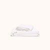 A white organic matte sheet set on  presented in a neat tidy pile against a white background.