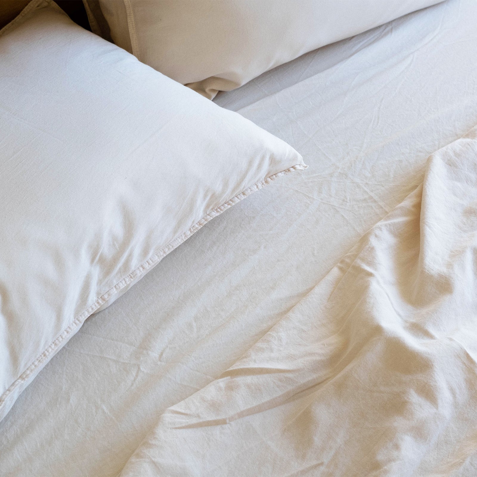 Close up of an Oat / cream colored pillow in a bed with oat sheets. 