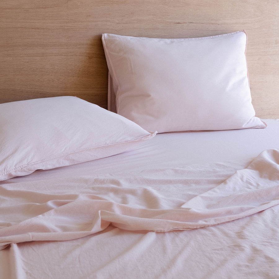 A bed dressed with two organic matte sateen pillows and sheets in Blush