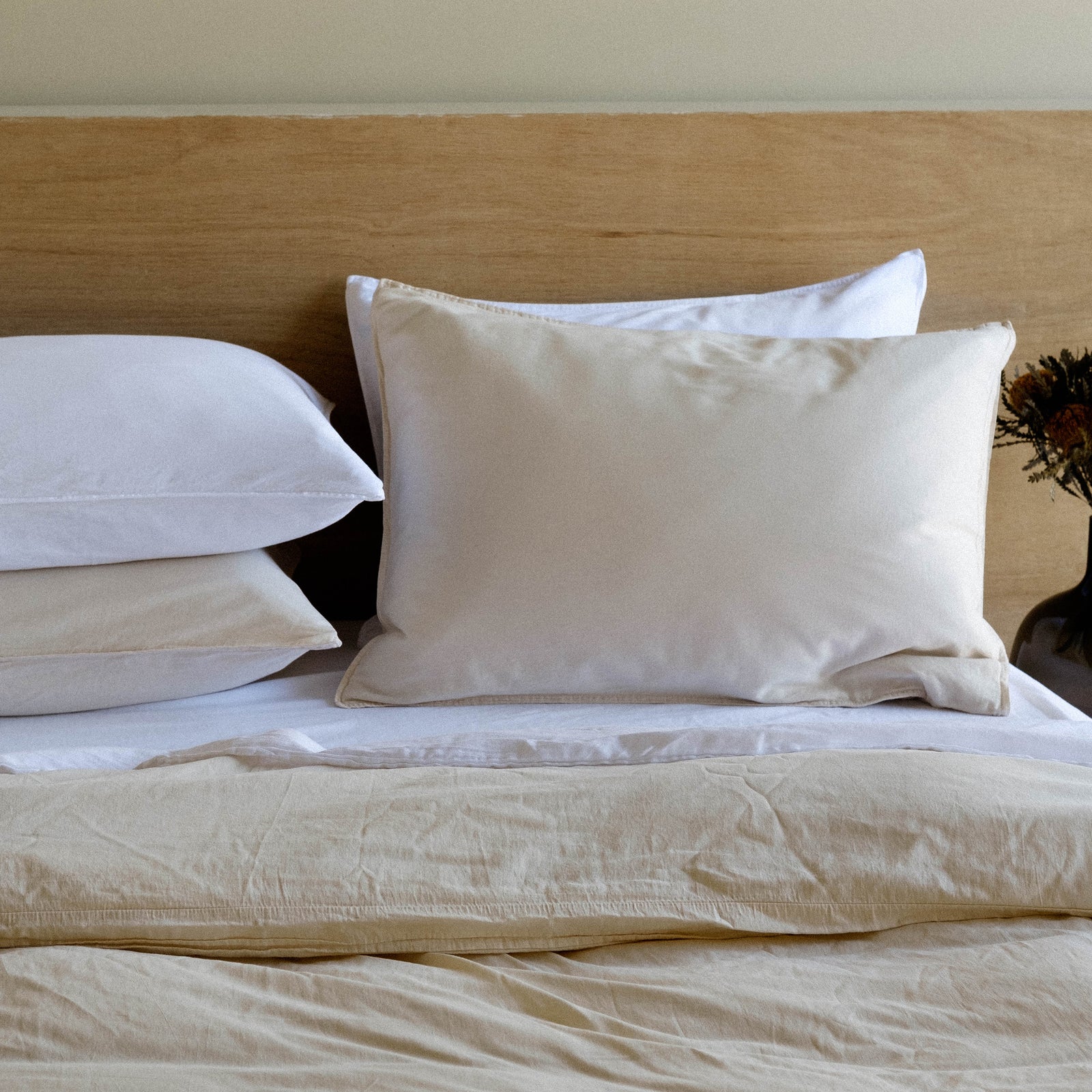 Pillows in beige and white resting against a wooden headboard in a bedroom setting 