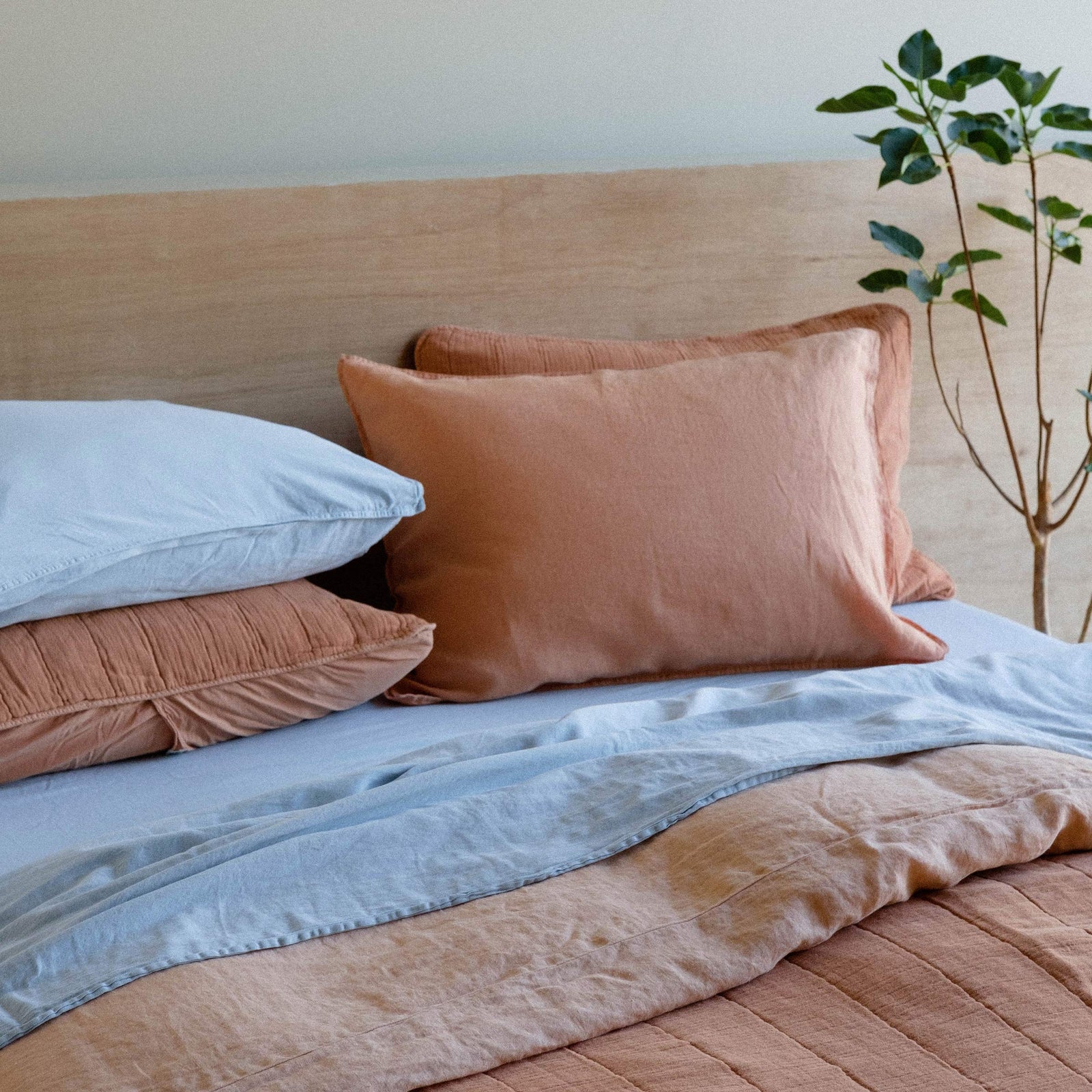 A bed with both Turkish Blue sheets and a pillow paired with orange sheets and matching pillows